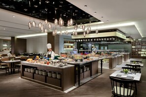 A modern restaurant with a central island, multiple dining tables, and hanging pendant lights. - Courtyard by Marriott Changsha South (Changsha)