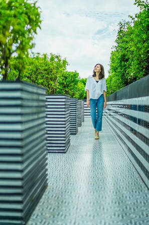 A person walking on a bridge with metal railings and greenery on both sides. - Holiday Inn Express Bangkok Soi Soonvijai by IHG (Bangkok)