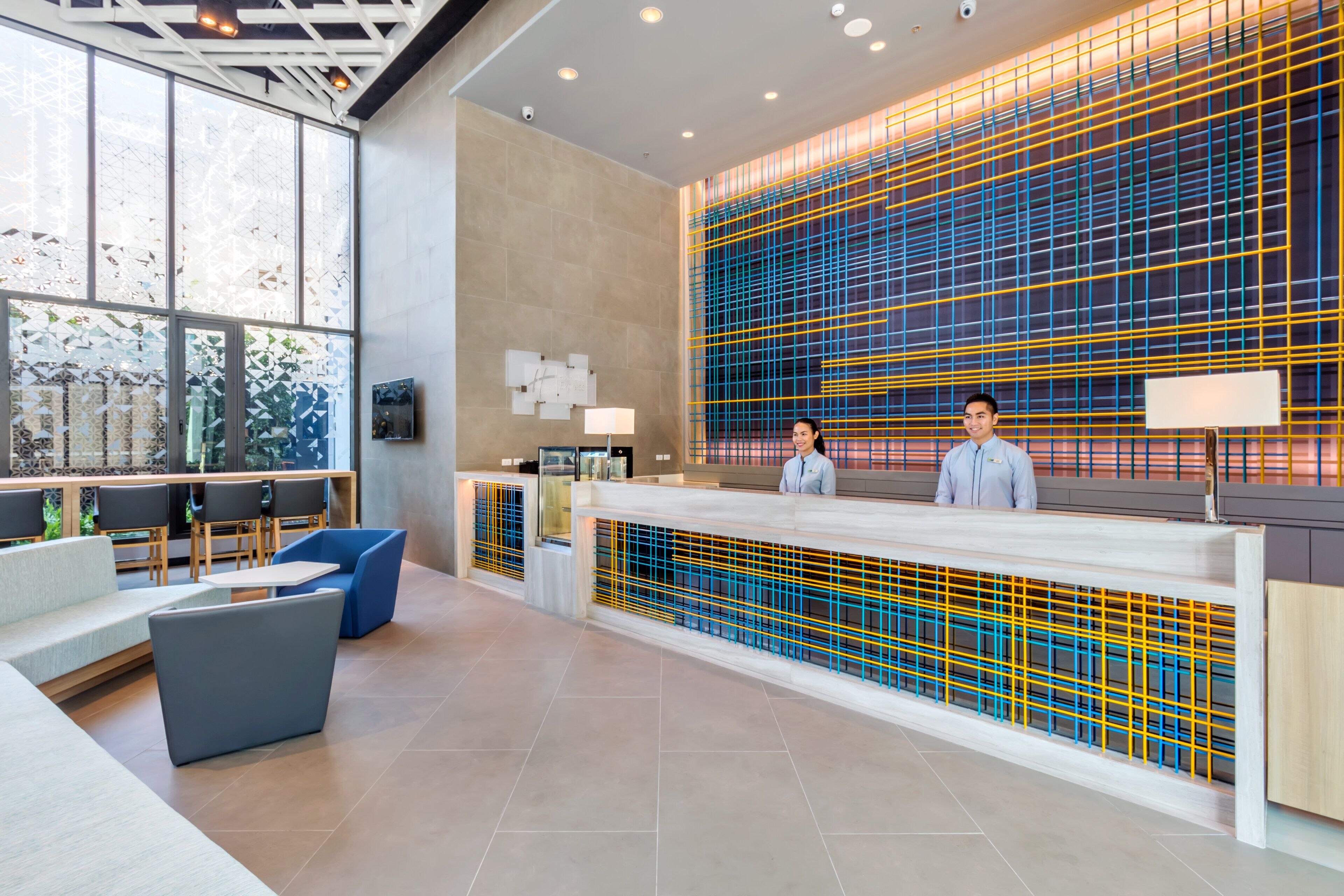 A modern reception area with a large window, seating, and a decorative wall.