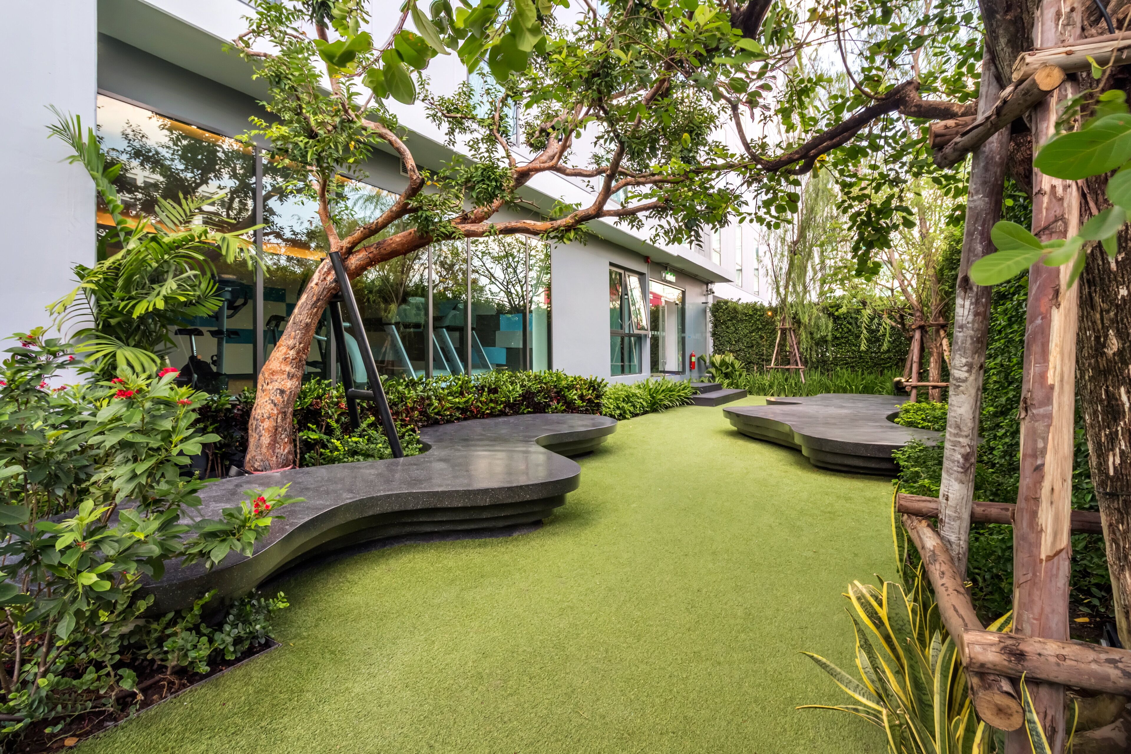 A landscaped garden with a curved pathway, artificial grass, and various plants.