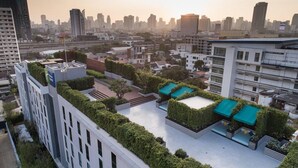 A rooftop garden with multiple seating areas and a view of the city skyline. - Holiday Inn Express Bangkok Soi Soonvijai by IHG (Bangkok)