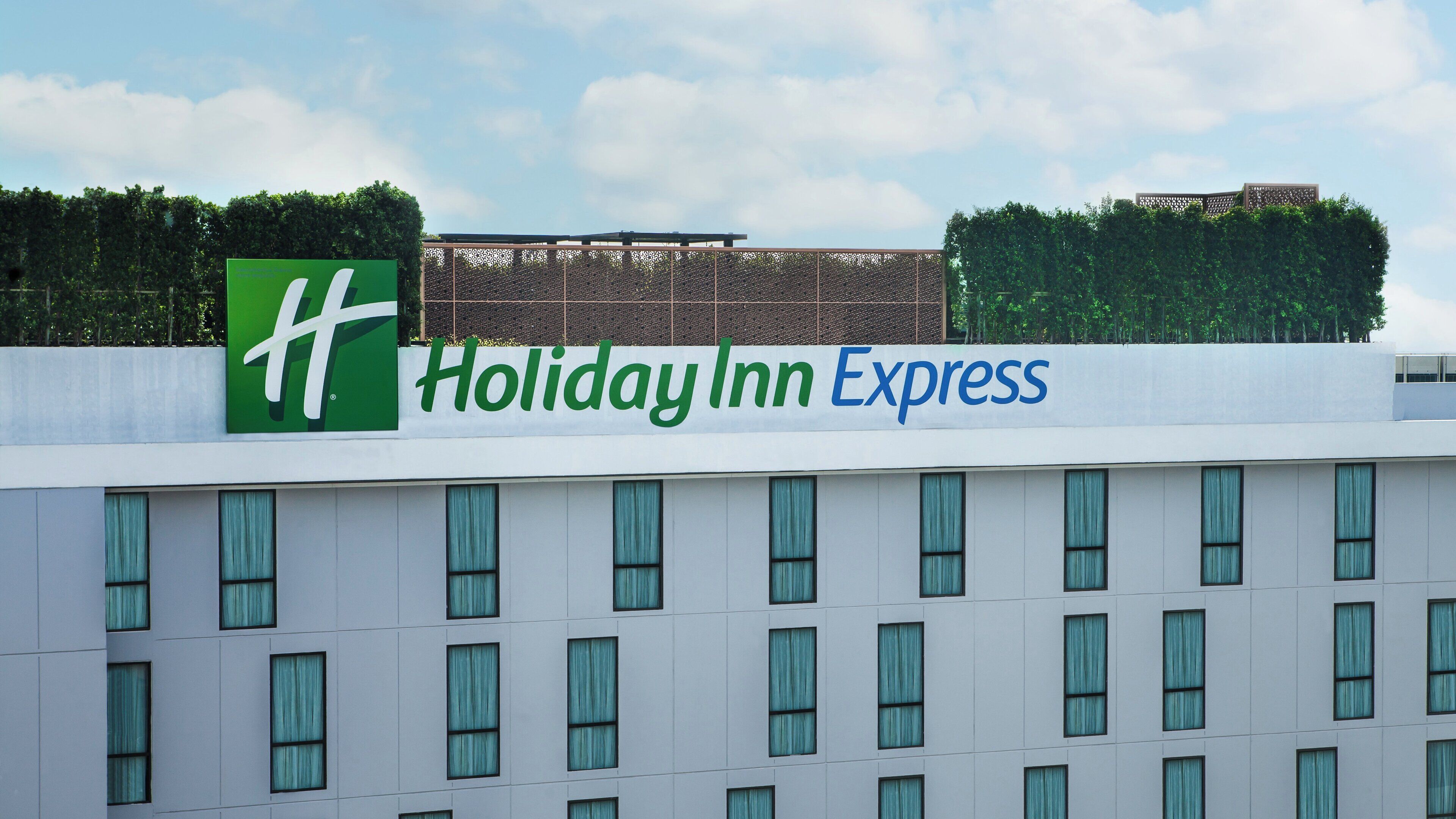 Une enseigne Holiday Inn Express sur un bâtiment à la façade moderne et doté de nombreuses fenêtres.