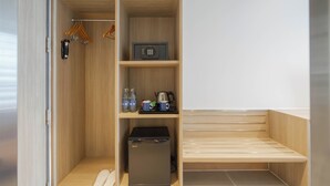 A walk-in closet with wooden shelves, a safe, a coffee maker, and a compact refrigerator.