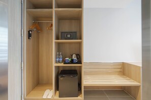A walk-in closet with wooden shelves, a safe, a coffee maker, and a compact refrigerator. - Holiday Inn Express Bangkok Soi Soonvijai by IHG (Bangkok)