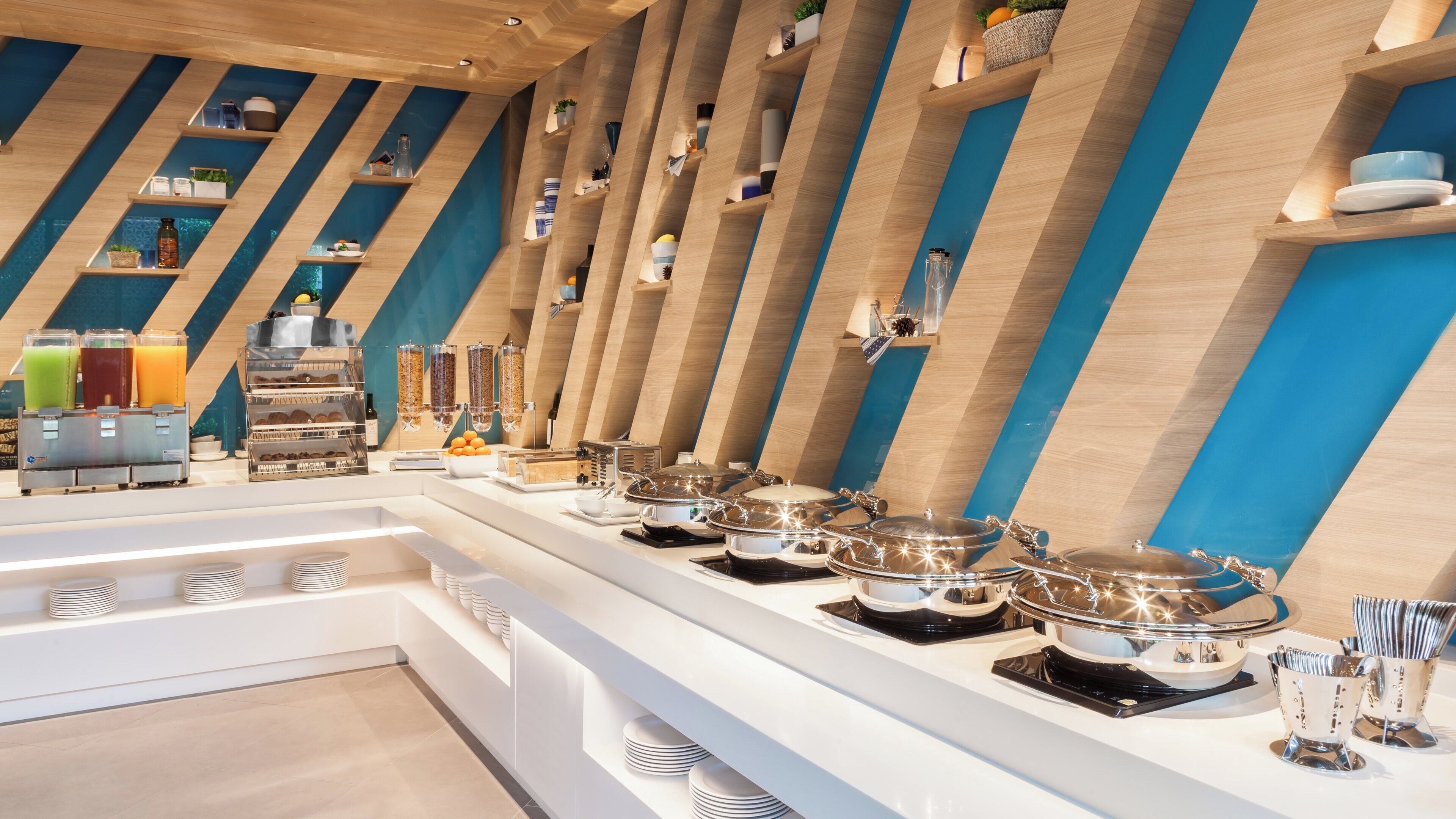 A buffet setup with multiple serving stations, a beverage dispenser, and a variety of food containers.