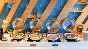 A buffet with four hot food stations, each with a metal lid and a sign indicating the type of food. There are small signs with food names and a sign for a special dish. - Holiday Inn Express Bangkok Soi Soonvijai by IHG (Bangkok)