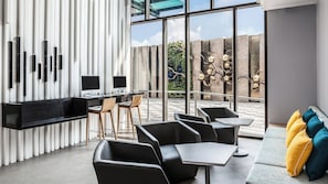 A modern interior with a long dining table, black chairs, and a sofa with colorful cushions.