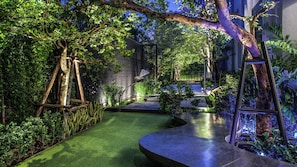 A garden with a curved pathway, trees, and a metal sculpture.