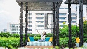 A person sitting on a swing with a cityscape in the background. - Holiday Inn Express Bangkok Soi Soonvijai by IHG (Bangkok)