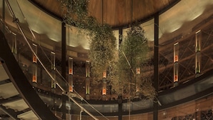 A multi-level wine cellar with a spiral staircase, wooden shelves, and a dining area with a glass table and chairs.
