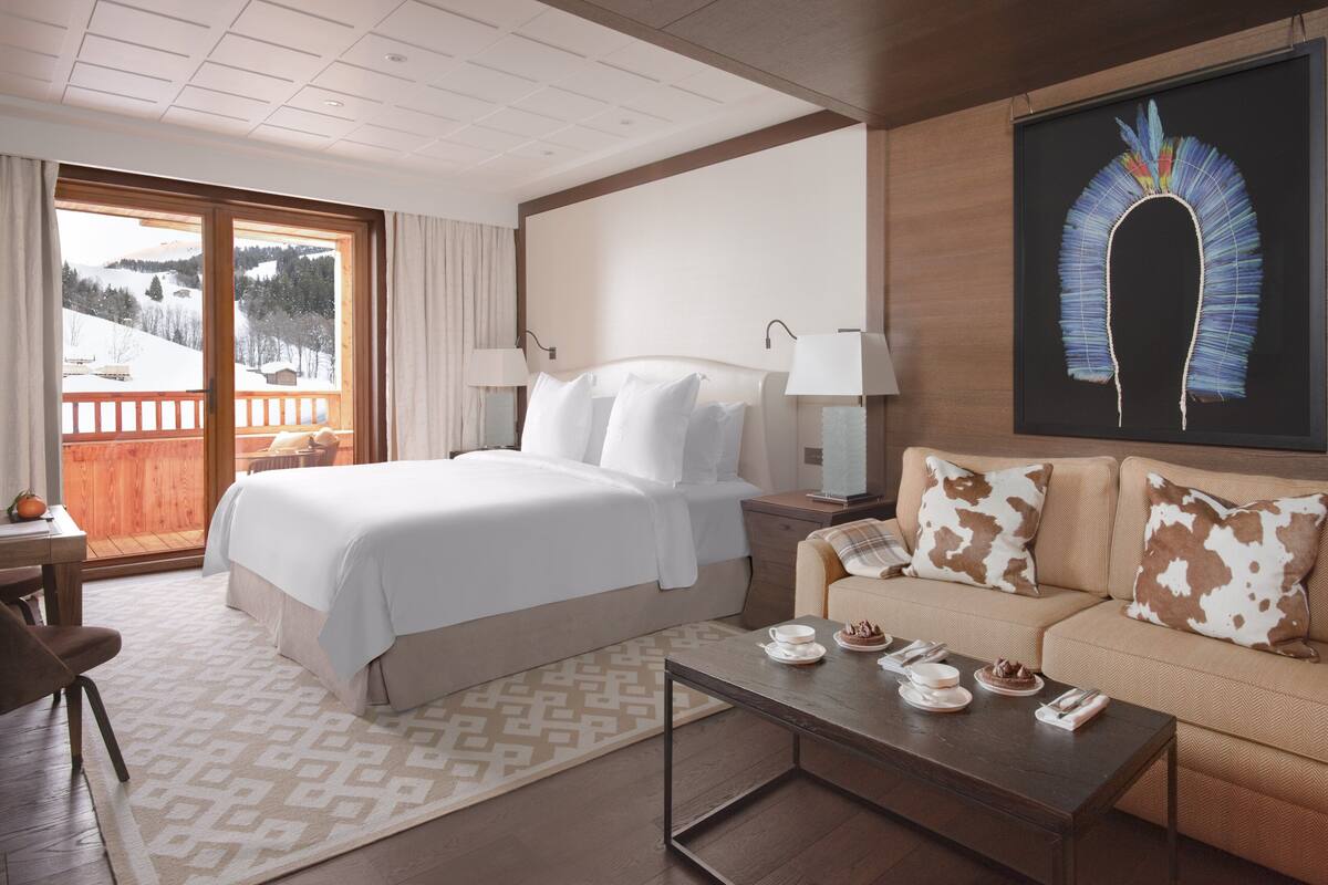 A hotel room with a bed, a sofa, a coffee table, and a painting on the wall.