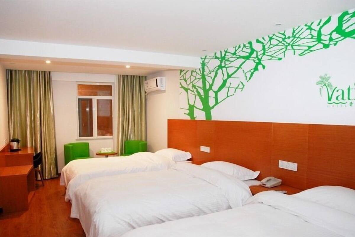 A hotel room with two beds, a desk, a chair, and a window with curtains.