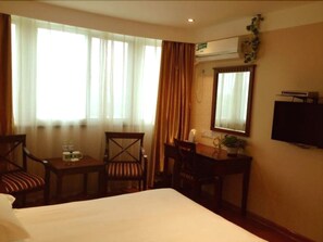 A hotel room with a bed, two chairs, a small table, a TV, and an air conditioning unit. - GreenTree Inn Yangzhou Jiangdu West Changjiang Road Liberty Park Business Hotel (Yangzhou)