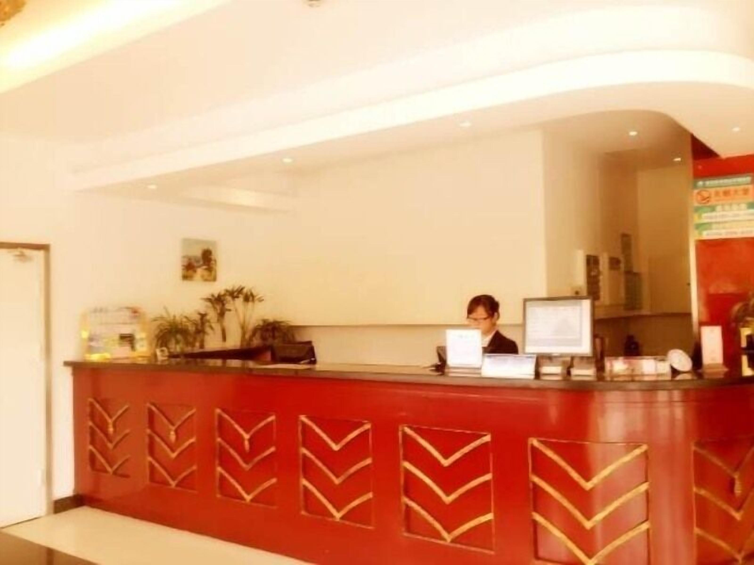 A reception desk with a red and gold chevron pattern, a computer, and a framed picture on the wall.