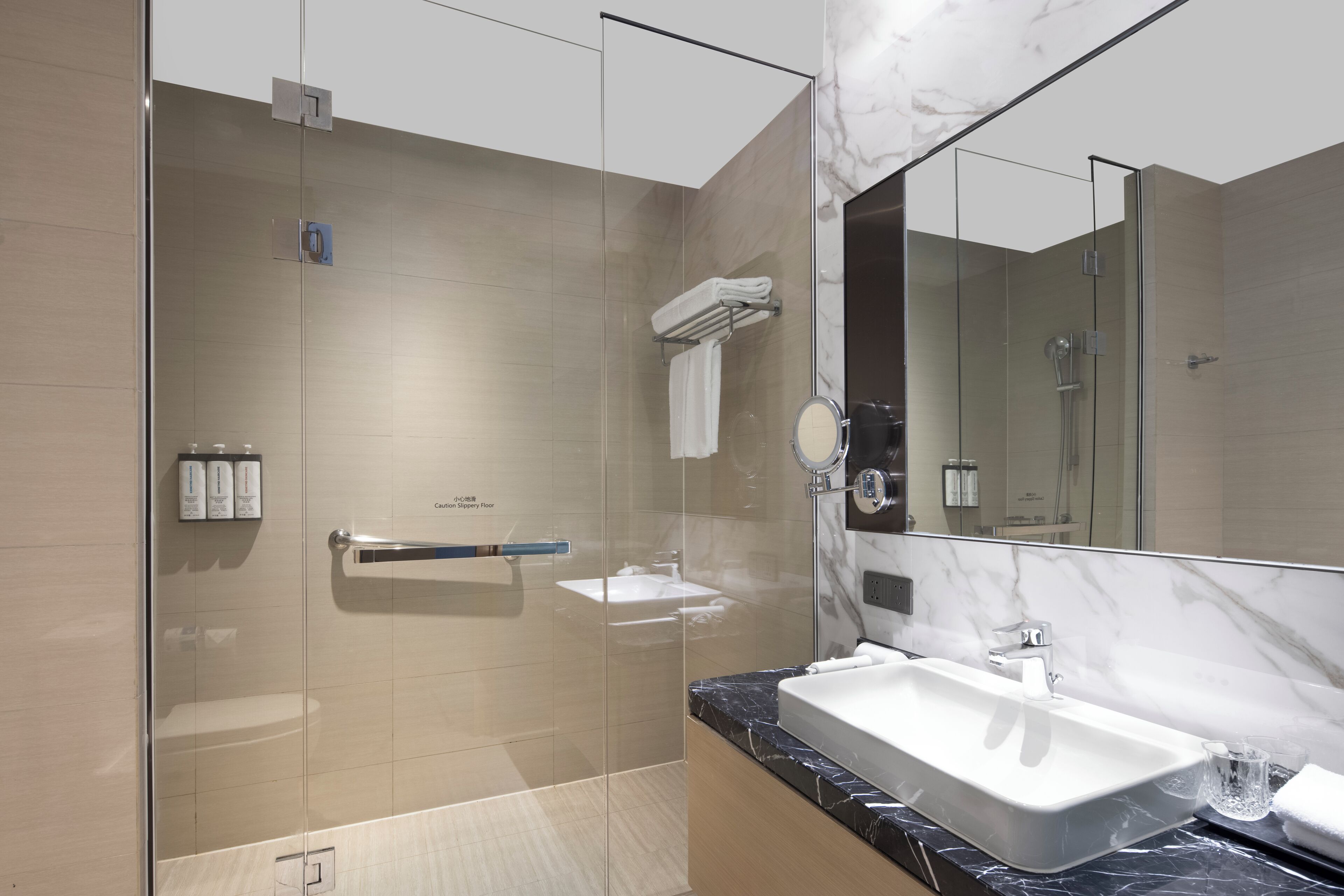A modern bathroom with a glass-enclosed shower, a marble countertop, and a large mirror.