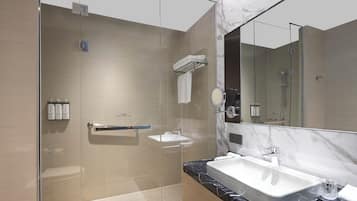 Un baño moderno con ducha envuelta en vidrio, encimera de mármol y un espejo grande.