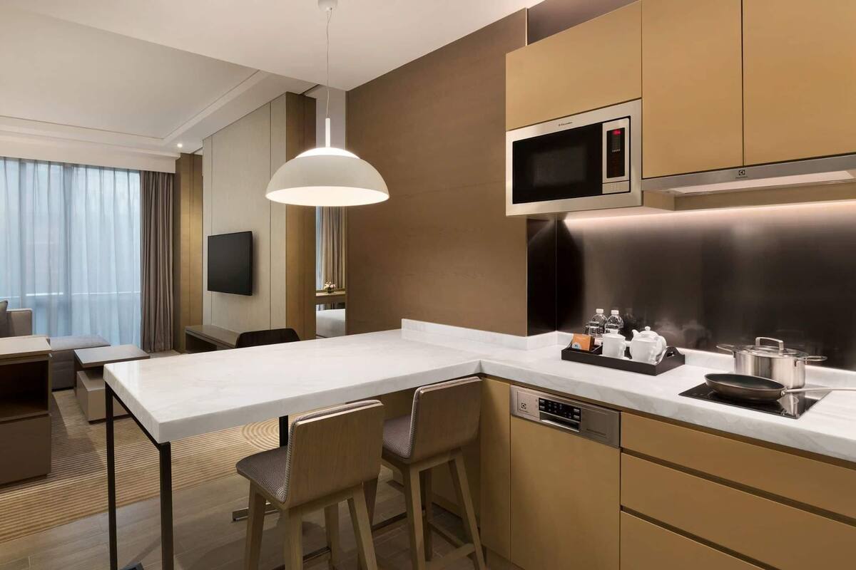 Une chambre d’hôtel moderne dotée d’une kitchenette, d’un coin repas et d’un téléviseur fixé au mur.