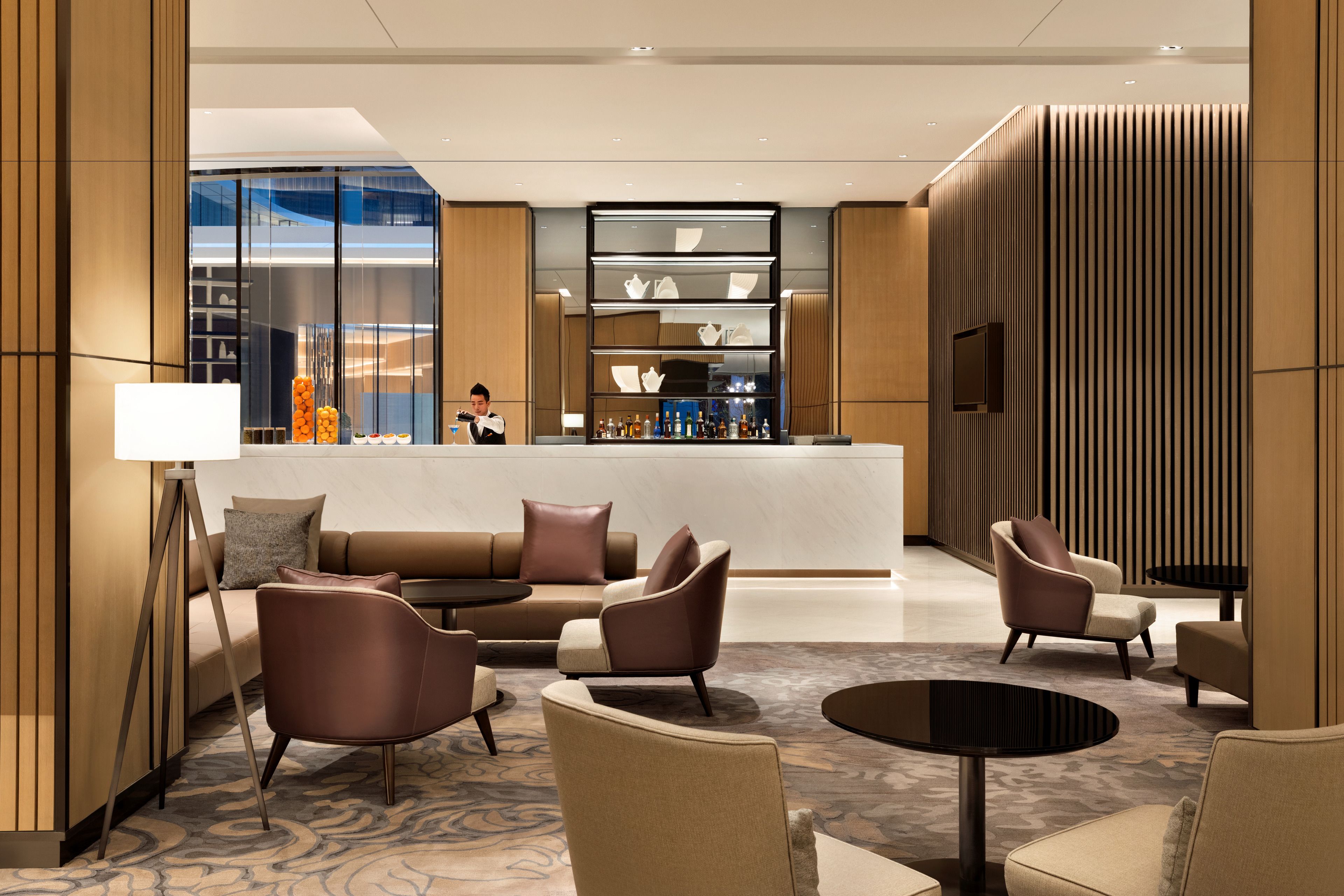 A modern lobby with a reception desk, seating area, and a bar.