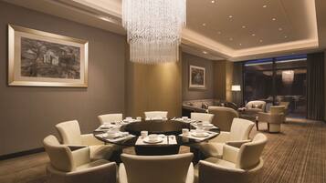 A modern dining area with a round table, comfortable seating, and a decorative chandelier.