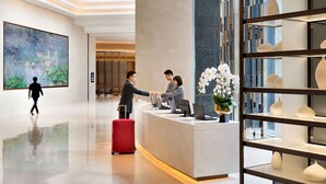 A modern hotel lobby with a reception desk, a large abstract painting, and a decorative shelf with vases. - Hyatt Place Shanghai Hongqiao CBD (Shanghai)