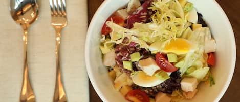 Eine Schüssel mit Salat und verschiedenen Zutaten auf einem Holztisch.