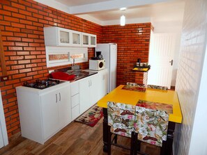 Compact kitchen with brick wall design, white cabinetry, and a dining table.
