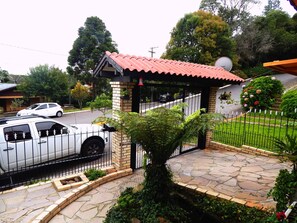 Stunning entrance with a brick column, red-tiled roof, and beautifully manicured lawn.