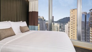 A hotel room with a large bed, a view of city buildings, and a window with curtains. - Hotel 108 (Kowloon)