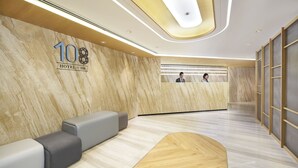 A modern hotel reception area with a marble wall, a reception desk, and seating. - Hotel 108 (Kowloon)