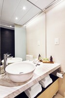 A modern bathroom with a large white sink, a mirror, and a black accent wall.