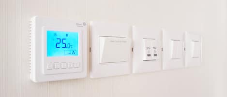 Un thermostat mural doté d’un écran numérique, d’un logement pour carte et d’un interrupteur d’alimentation.