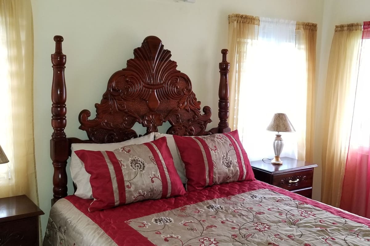 A bedroom with a wooden bed, two bedside tables, and curtains.