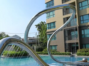A modern building with a pool and a unique water feature. - Rain Cha-Am Hua Hin by D-light (Cha-am)