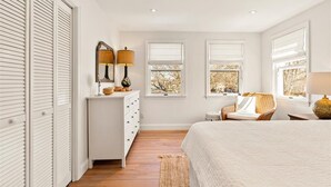 A bedroom with a bed, dresser, two windows with blinds, a chair, and a lamp. - Walk To Town - Beautiful Edgartown House  (Edgartown)