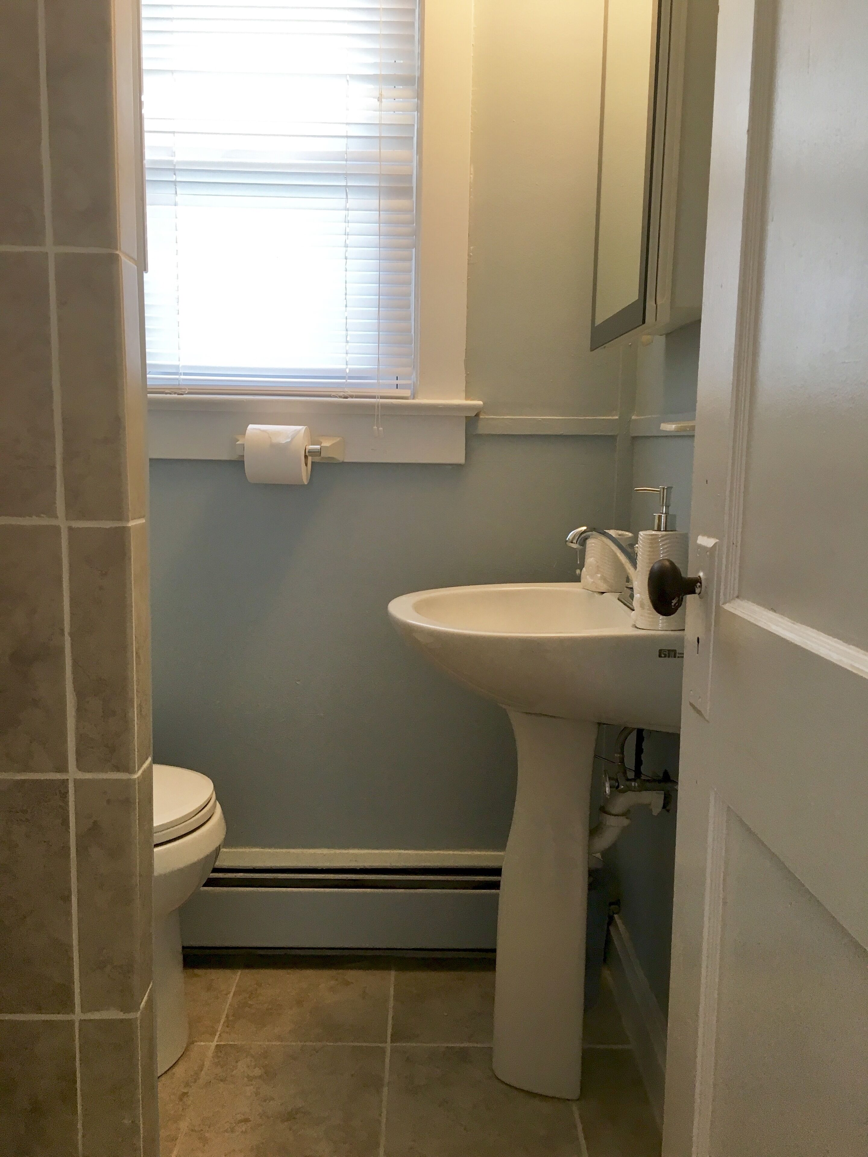 Ein Badezimmer mit Toilette, Waschbecken und einem Fenster mit Jalousien.
