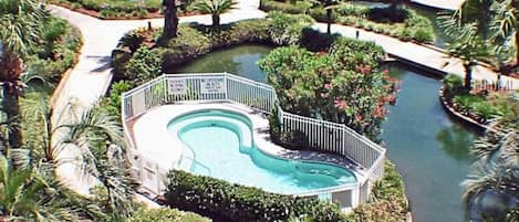 Relax by the resort's curved pool surrounded by lush greenery and palm trees.