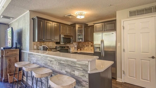 A kitchen with a large island, bar stools, a refrigerator, and a microwave. - 2201 SeaCrest. Renovated 1BR + Bunk Alcove — 2 Full Baths, Sleeps 6 (Hilton Head Island)