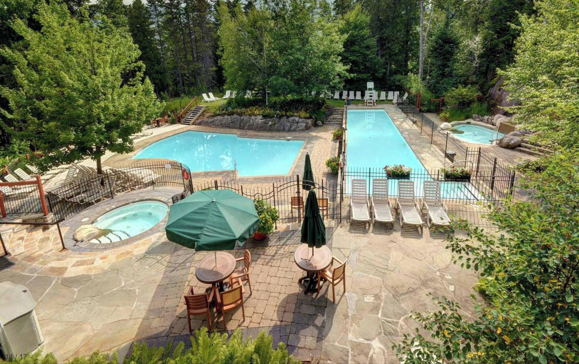 A pool area with multiple pools, lounge chairs, and a hot tub.