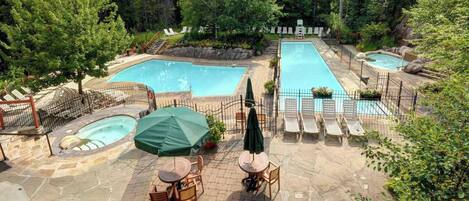 A pool area with multiple pools, lounge chairs, and a hot tub.