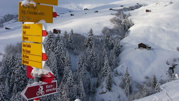 A snow-covered mountain with a signpost indicating directions to various ski runs and facilities. - Sunny Apartment With Terrace In Idyllic Setting, 2 Bedrooms, Sleeps 4 (Lumnezia)