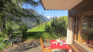 A patio with a table and chairs, a bicycle, and a view of mountains. - Sunny Apartment With Terrace In Idyllic Setting, 2 Bedrooms, Sleeps 4 (Lumnezia)