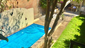 A swimming pool with a brick wall and a grassy area. - 2BED/2BA, Pool, Lush Gardens, Private Rooftop, Walk to Beach & Downtown (Bucerías)