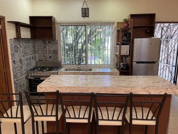 A kitchen with a large island, a stove, and a refrigerator. - 2BED/2BA, Pool, Lush Gardens, Private Rooftop, Walk to Beach & Downtown (Bucerías)