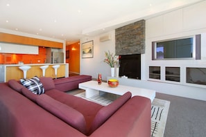 A modern living room with a sectional sofa, a white coffee table, and a fireplace. - Penthouse St Kilda Style (St Kilda)