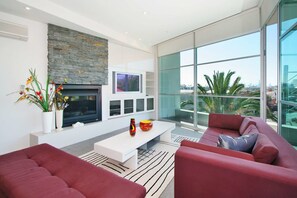 Una sala de estar moderna con chimenea, ventanas amplias y un sofá rojo.