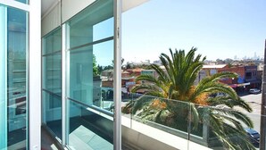 A modern building with large glass windows and a view of a cityscape with palm trees. - Penthouse St Kilda Style (St Kilda)