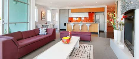 A modern living room with a red sofa, a white coffee table, and a kitchen in the background.