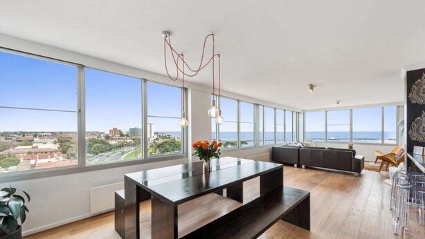 A spacious living area with a large dining table, a sofa, and a view of the city. - St Kilda Penthouse with Panaromic Bay and City View (St Kilda West)