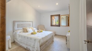 Een slaapkamer met een bed, een stoel, een klein tafeltje, een spiegel en een radiator.