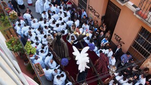 A group of people gathered around a religious procession with a figure on a platform, surrounded by onlookers.